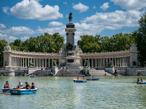 People enjoy boating at the iconic Retiro Park with Alfonso XII Monument, Madrid.