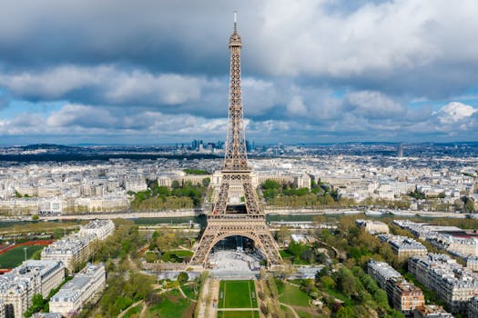 pexels-photo-8430379-8430379 Stunning aerial view of the Eiffel Tower amidst the Paris cityscape under cloudy skies.