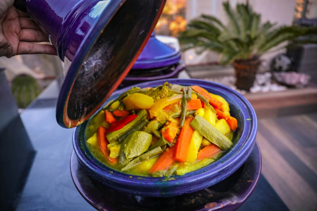 Vibrant vegetable tajine served in a traditional purple pot with a variety of fresh ingredients.